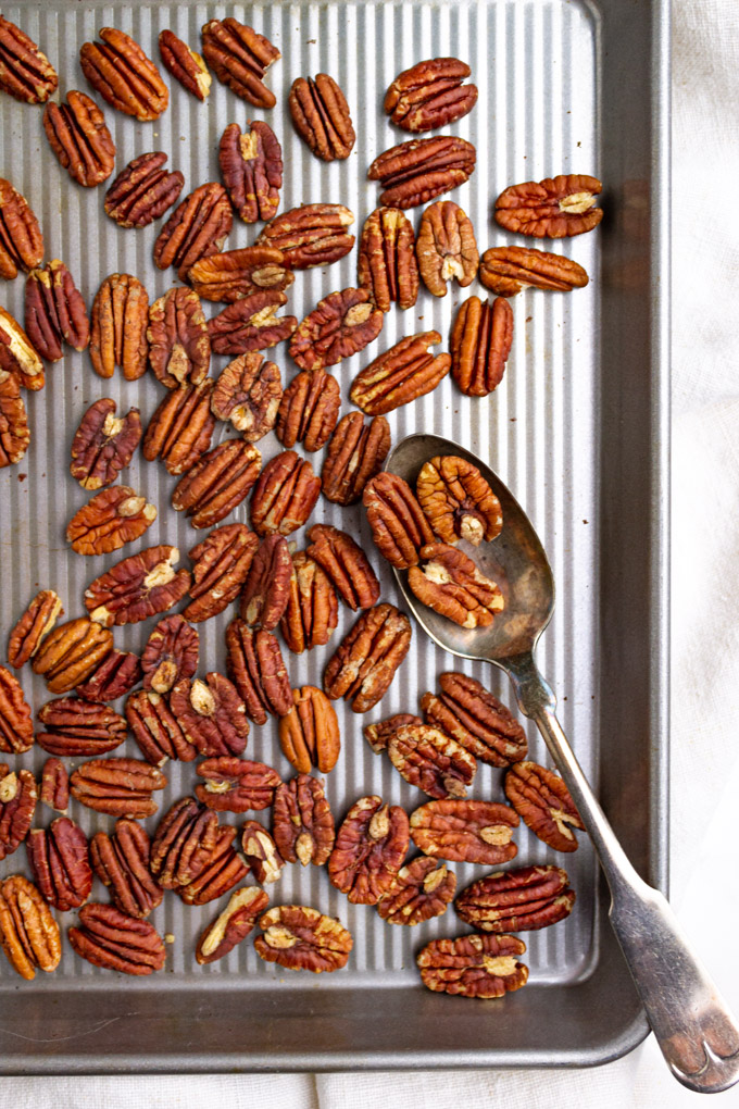 toasted pecans on a sheet pan, with a spoon.