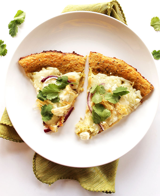 Green Chicken Enchilada Pizza - It's pretty much an enchilada on a pizza. Roasted green enchilada sauce, cheese, red onions, chicken, cilantro all on top of a crispy easy cauliflower crust! This recipe is husband approved! | robustrecipes.com