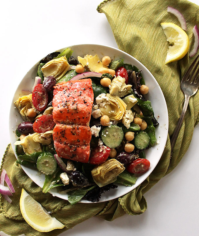Easy Greek Salmon Salad - Fresh lettuce greens topped with all your Greek fixin's, tossed with a creamy Greek dressing and topped with a hunk of pan seared salmon. This recipe is EASY - perfect for a weeknight meal. Gluten free.