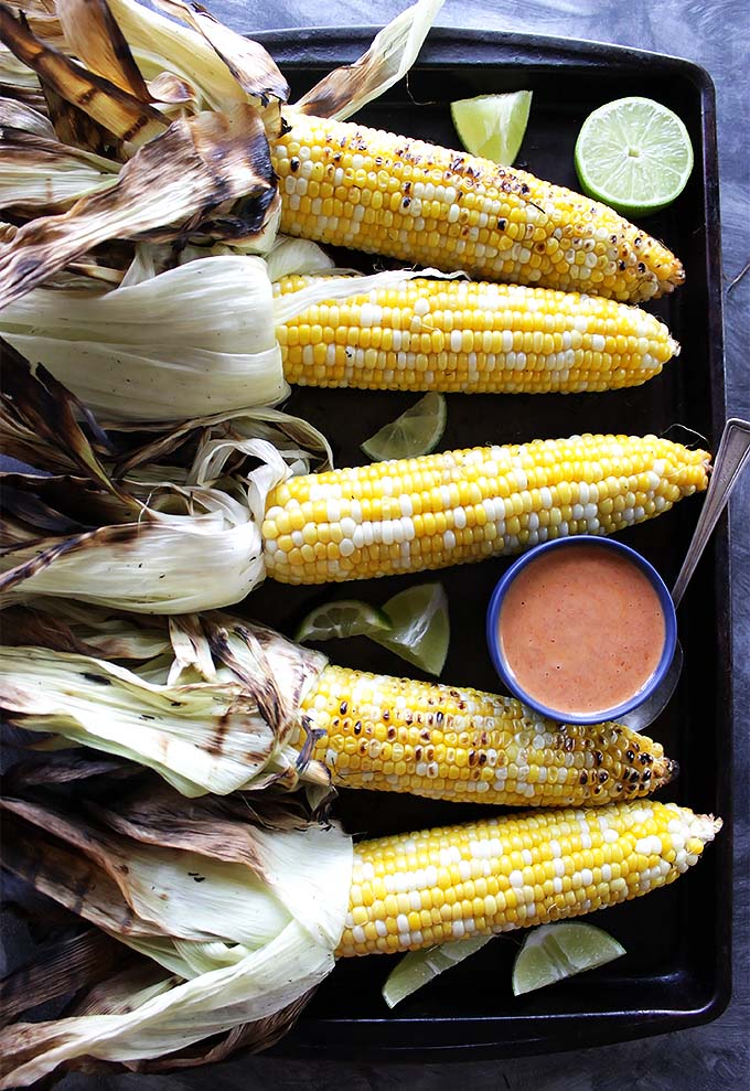 Grilled Corn with Spicy Chipotle Sauce - Sweet Corn that's drizzled with a smoky/sweet/spicy sauce and topped with cilantro and lime. EASY to make. This recipe is perfect for summertime parties! vegetarian/gluten free