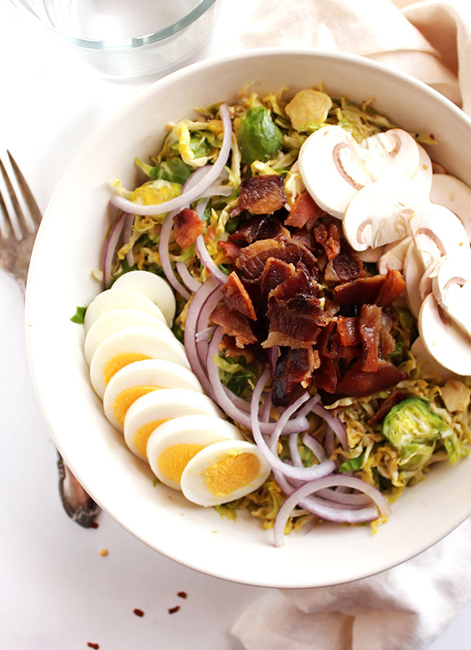 Brussels Sprouts Salad with Warm Bacon Dressing - Crunchy shredded Brussels Sprouts are tossed in a warm, smoky bacon dressing. All of that goodness is topped with red onion, hard boiled egg, and mushrooms! SO GOOD! This recipe is perfect as a side salad or an entree salad. Gluten Free/Dairy Free | robustrecipes.com