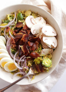 Brussels Sprouts Salad with Warm Bacon Dressing - Shredded Brussels sprouts tossed an a warm bacon dressing and topped with hard boiled eggs, red onion, sliced mushrooms and BACON! This recipe is perfect as a side or dinner salad. Gluten Free/Dairy Free | robustrecipes.com