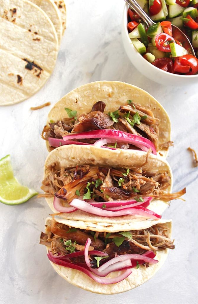 Slow Cooker Spicy Carnitas - Pork cooked until it's melt-in-your-mouth tender and then cooked under a broiler until it crisps up a little. Topped with a simple cucumber tomato pico de gallo and picked onions. This recipe is great for meal prep or feeding a crowd. The pork also freezes really well. Gluten Free/Dairy Free | robustrecipes.com