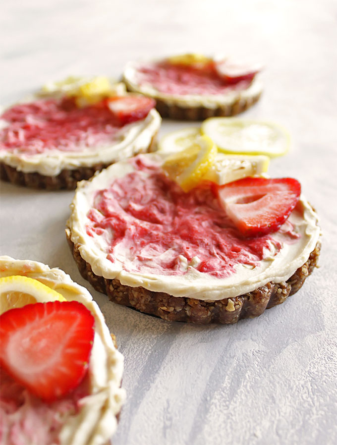 Mini vegan Lemon Strawberry Cheesecakes - These mini cheesecakes are perfect for parties or celebrations. Or keep them on hand, in the freezer for any time you have a craving. This is a no bake recipe. The crust is a date/pecan crust and the filling is lemon-y with a strawberry swirl. Gluten Free/ Vegan/ Refined Sugar Free/ Dairy Free | robustrecipes.com
