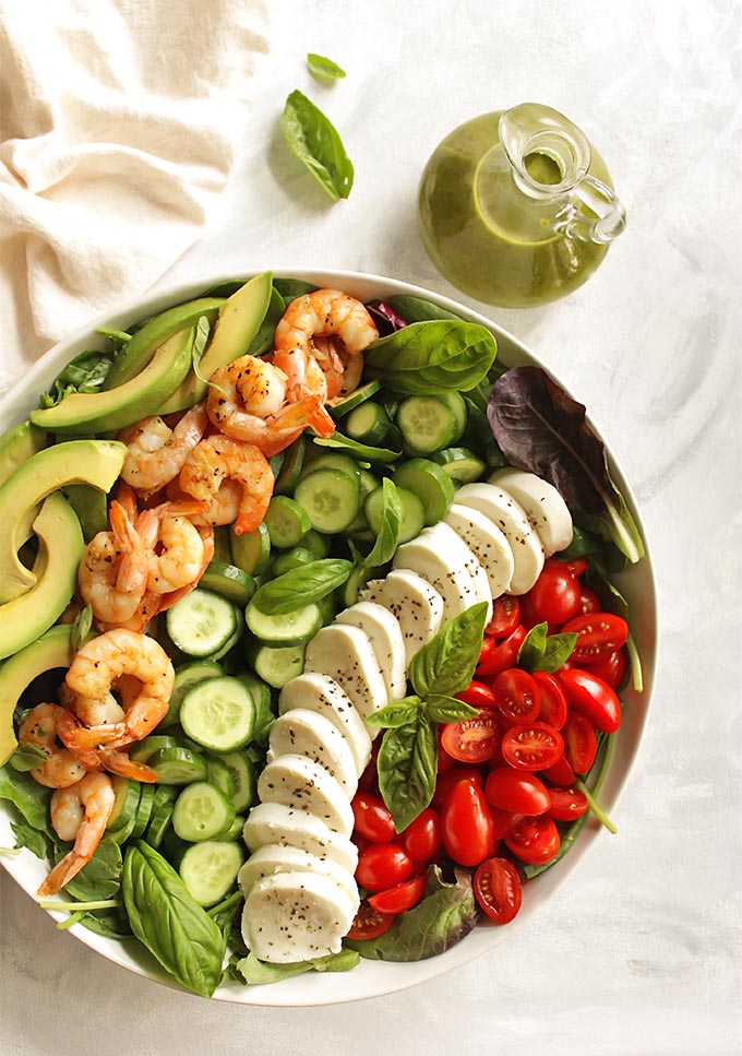 Loaded Caprese Salad with Shrimp - packed with all of the caprese classics plus some extra veggies. The salad is topped with a yummy basil dressing. This recipe only takes 25 minutes to make and is perfect for a quick dinner! Gluten free | robustrecipes.com