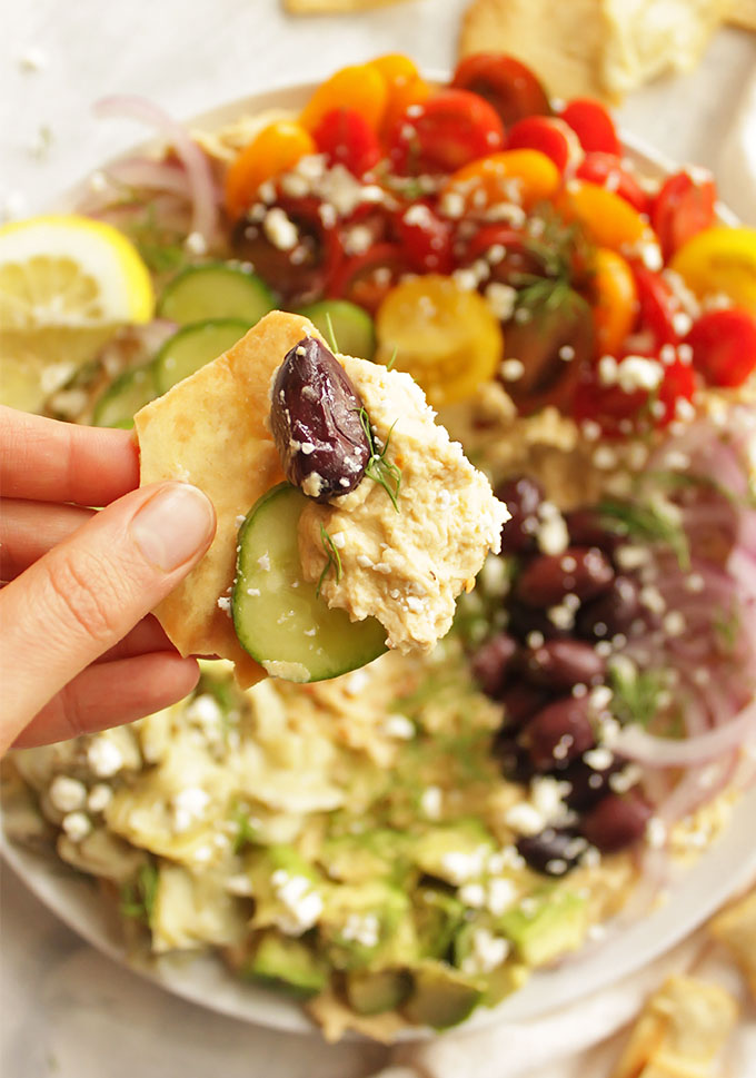 Creamy hummus topped with all the Greek fixings, artichoke hearts, tomatoes, cucumbers, red onion, kalamata olives, feta cheese, avocado, and fresh dill. It's served with sturdy pita chips or gluten free crackers for the ultimate dipping experience. Loaded Greek hummus only takes 20 minutes to make! The perfect appetizer for any party. (Gluten Free & Vegetarian) | robustrecipes.com