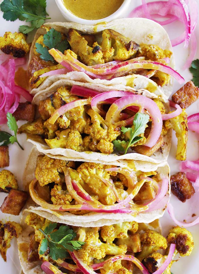 Curried cauliflower tacos with crispy tofu for the ultimate vegan taco night. Topped with crunchy, tangy pickled onions and a creamy curry sauce. Comforting, satisfying, and fun to eat! This recipe is super easy to make, only takes 45 minutes! SO YUM!!! (gluten free/vegan/vegetarian) | robustrecipes.com