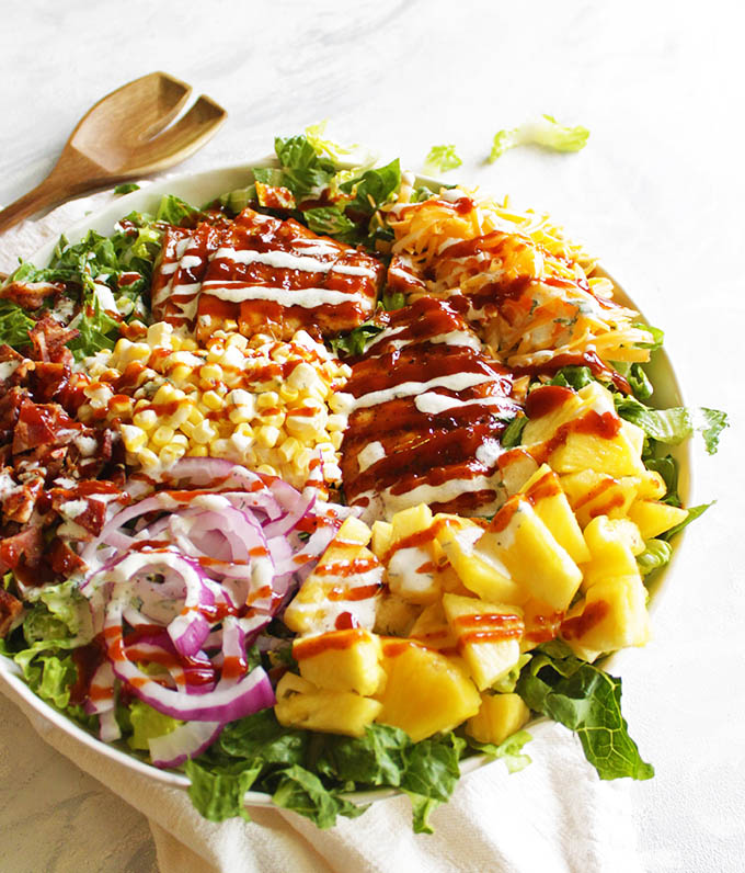 BBQ chicken salad is loaded with grilled BBQ chicken, corn, pineapple, smoked cheddar cheese, BACON, and topped with a homemade Greek yogurt ranch dressing and more BBQ sauce. The perfect dinner salad for summer! #BBQchicken #salad #chicken #summersalad #bacon #glutenfree | robustrecipes.com