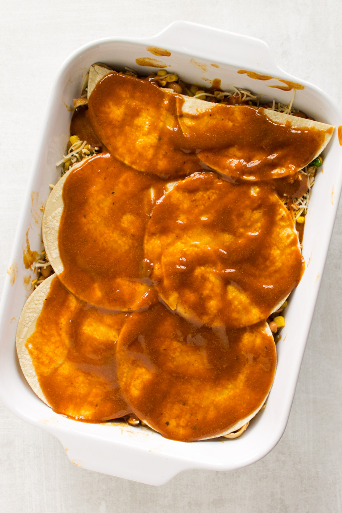 Easy Chicken Enchilada Casserole - all the enchilada flavors made into a casserole that's layered with corn tortillas. This casserole is perfect for feeding a crowd or meal prep. Makes great leftovers. #chicken #recipe #enchiladas #Mexicanfood #cincodemayo #glutenfree #corn #cleaneating #healthyfood #cheese #mealprep | robustrecipes.com