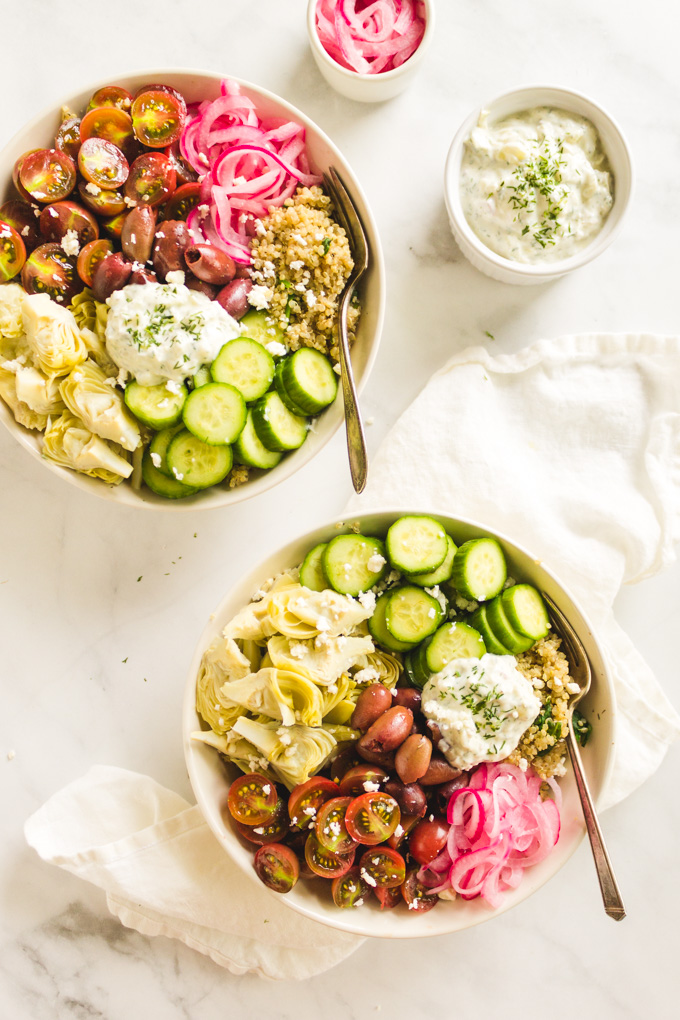 Greek Quinoa Bowls with Tzatziki Sauce - loaded with tons of veggies. This is the perfect vegetarian weeknight meal. They are super delicious and great for summer! #glutenfree #quinoa #summer #Greekyogurt #pickledonions #spinach #cucumbers #vegetrian #easyrecipe #weeknightmeal #healthy #cleaneating #artichokehearts | robustrecipes.com