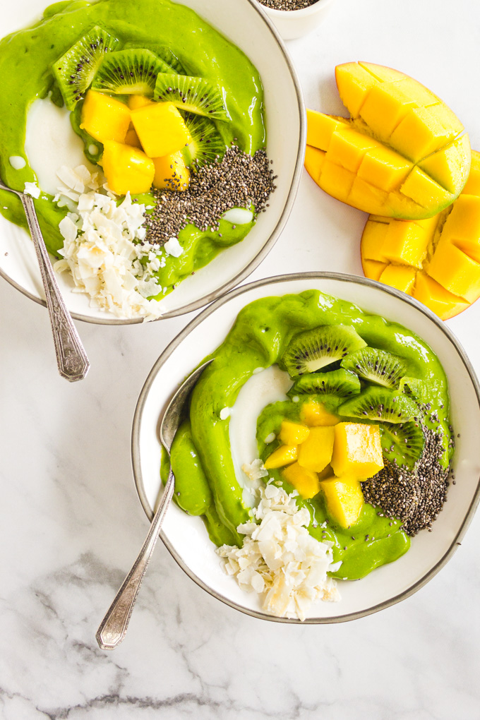 Mango Smoothie Bowl -  a thick and creamy smoothie bowl. Topped with fresh fruit, coconut flakes, coconut, butter, and chia seeds it's nutritious and delicious. #smoothiebowl #smoothierecipe #greensmoothie #mango #spinach #coconut #breakfast #veganrecipe #glutenfreerecipe #dairyfreerecipe #easyrecipe | robustrecipes.com