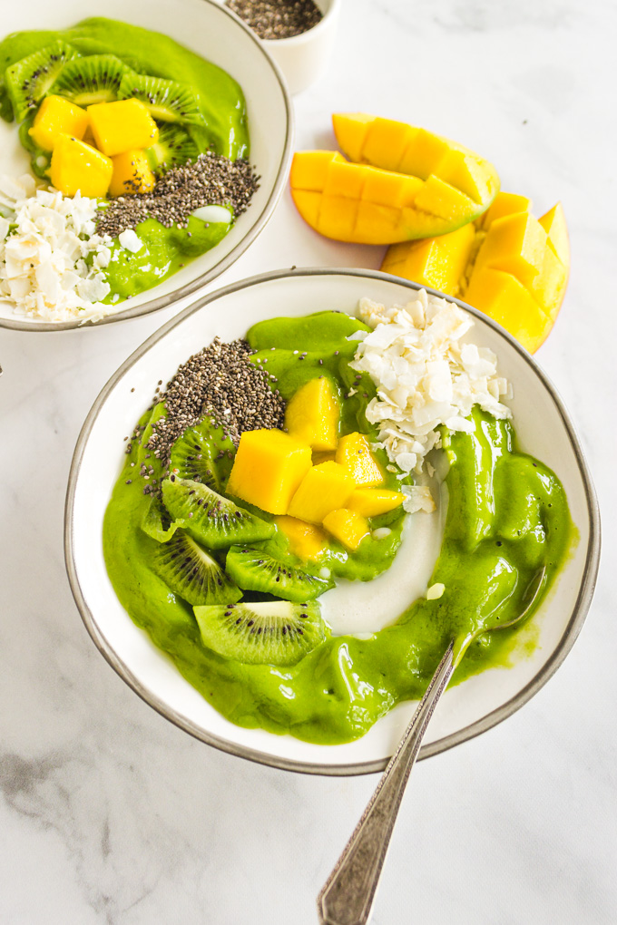 Mango Smoothie Bowl -  a thick and creamy smoothie bowl. Topped with fresh fruit, coconut flakes, coconut, butter, and chia seeds it's nutritious and delicious. #smoothiebowl #smoothierecipe #greensmoothie #mango #spinach #coconut #breakfast #veganrecipe #glutenfreerecipe #dairyfreerecipe #easyrecipe | robustrecipes.com