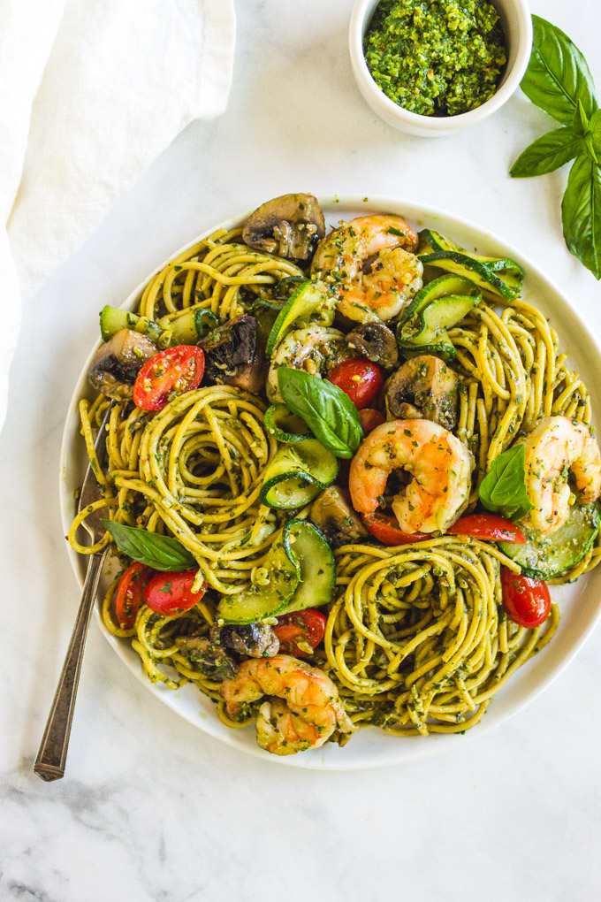 Summer pesto pasta with shrimp. A plate of pasts with pesto, shrimp, and veggies.