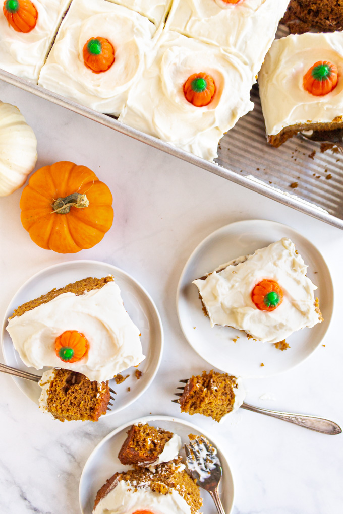 An overhead photo of slices of pumpkin cake with with cream cheese frosting and decorated with pumpkin candies.