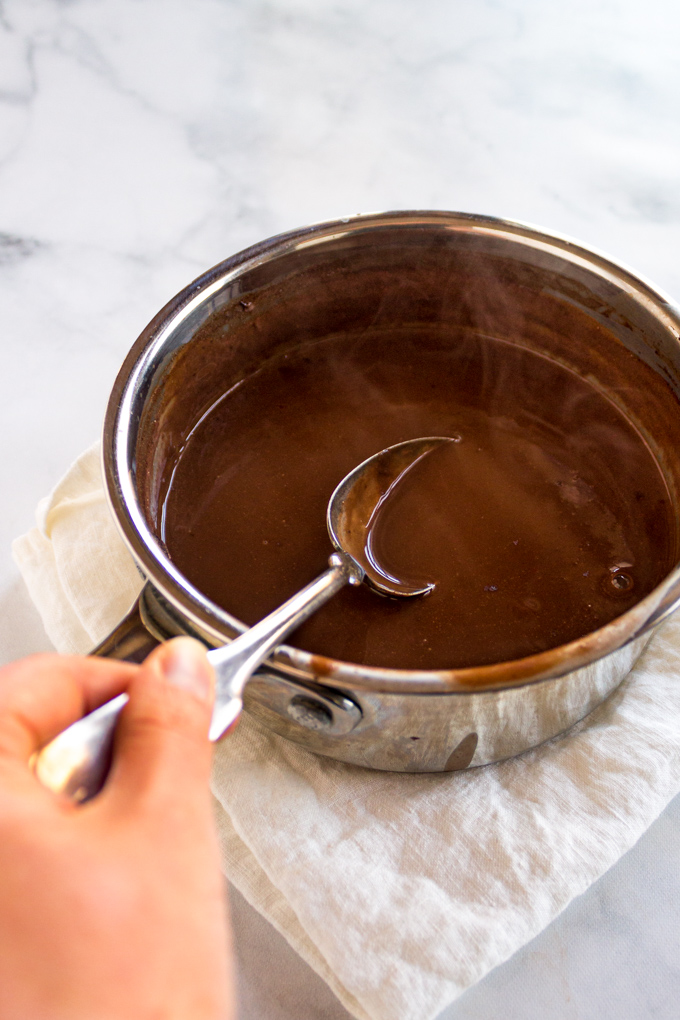 sideways view of homemade hot chocolate in sauce pan, with a spoon