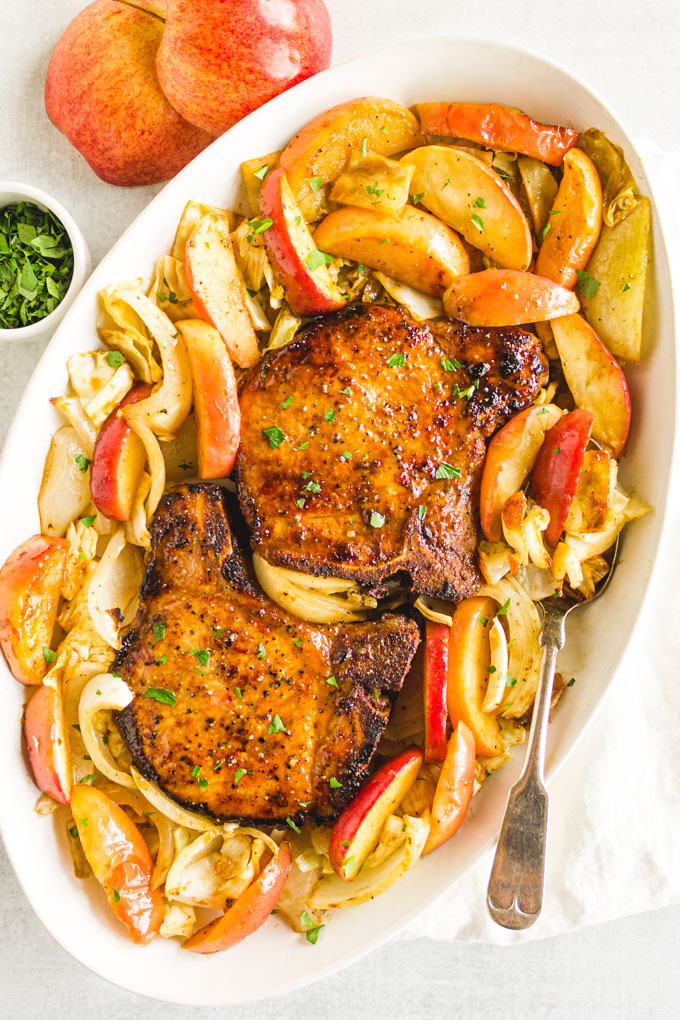 overhead of maple pork chops on a platter with roasted apples and cabbage