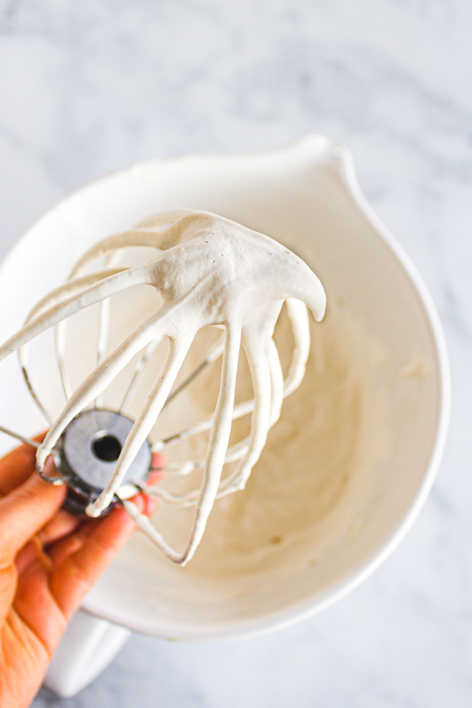 whipped cream on a whisk, showing soft peaks.