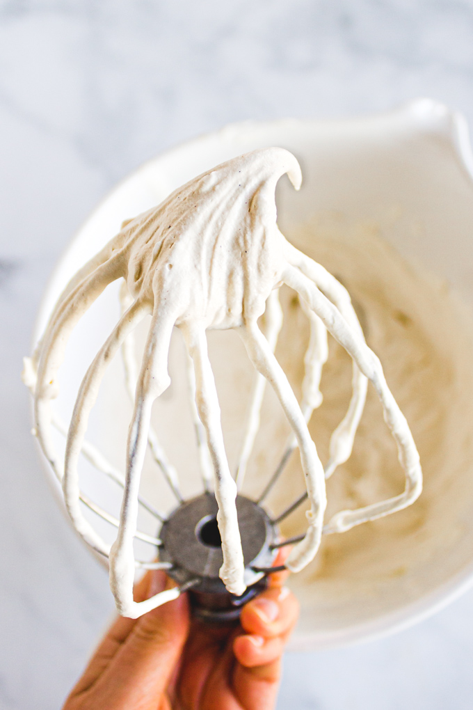 whipped cream on the whisk, showing stiff peaks.