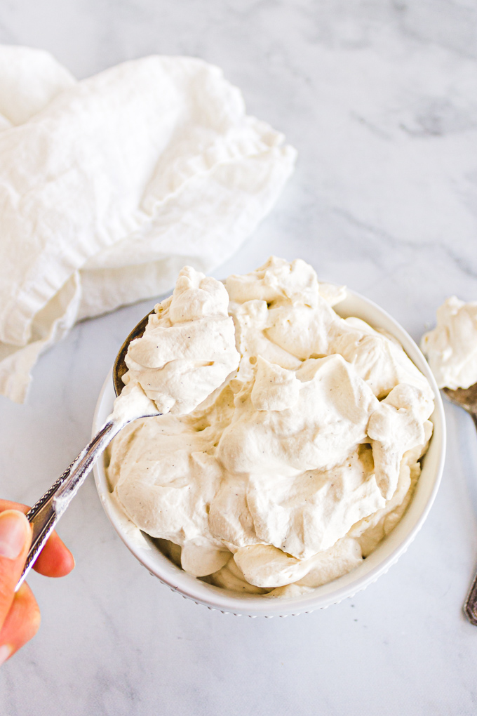 whipped cream in a white bowl with a spoon.