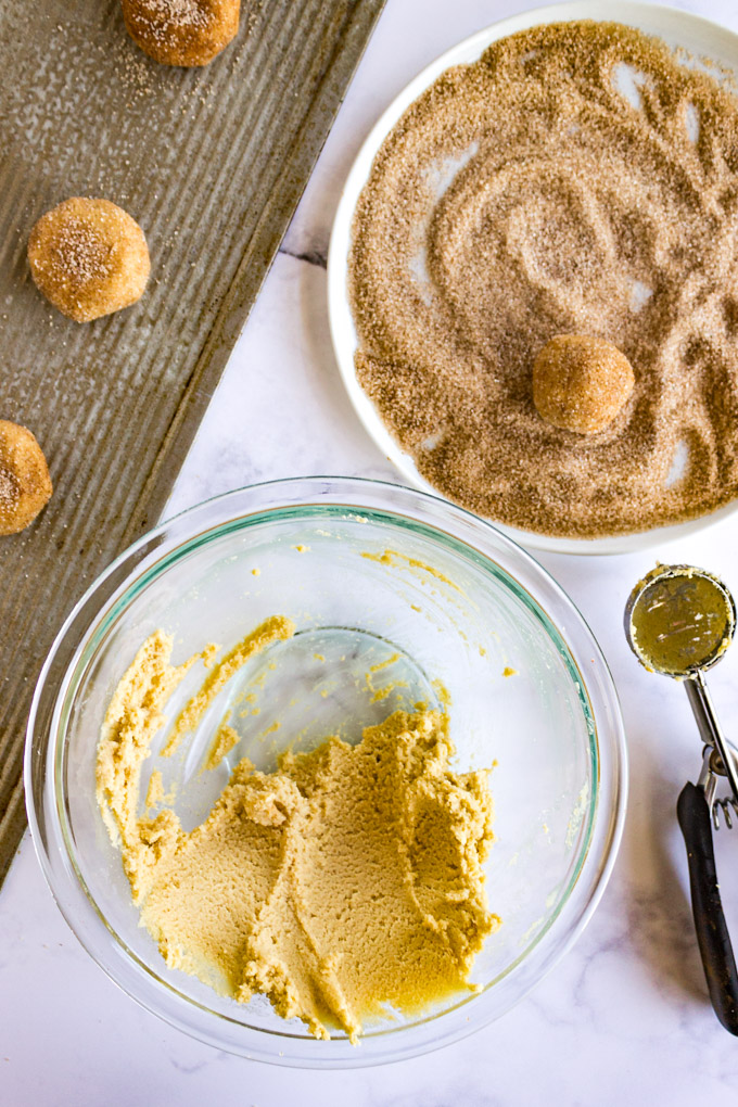 Snickerdoodle cookie dough scooped into balls and rolled into cinnamon and sugar mixture.