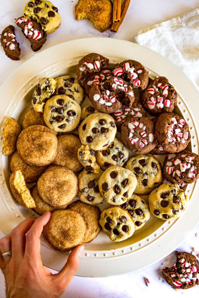 round platter of 3 Christmas cookies with a hand reaching for one cookie.