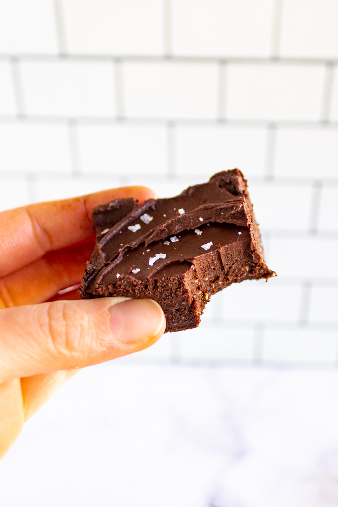 A no bake brownie with a bite taken out of the brownie and a hand holing in the air.