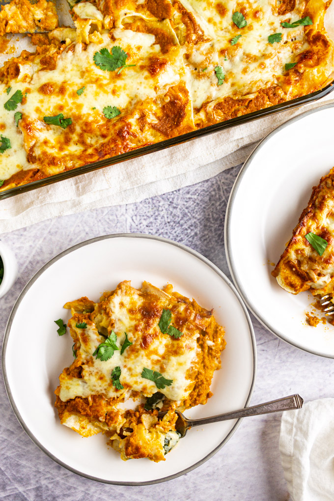Chili relleno enchiladas in a baking dish with a two servings on a plate.