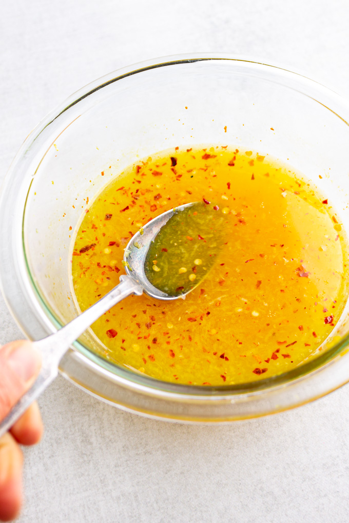 Orange sauce in a mixing bowl with a spoon stirring it.
