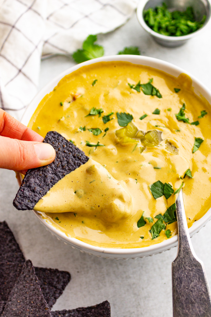 vegan cashew queso in a bowl with a tortilla chip dipping into the sauce.