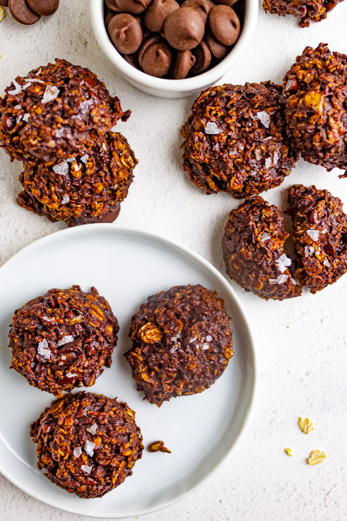 healthy chocolate oatmeal cookies on a plate , some are on a white background with a bowl of chocolate chips