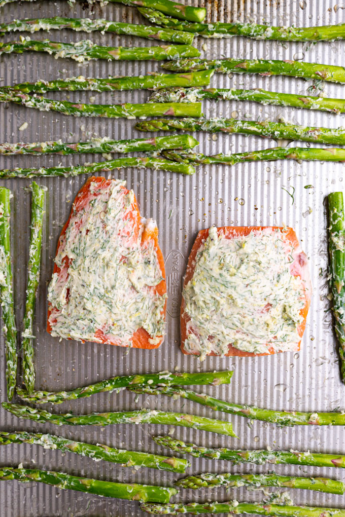 salmon and asparagus on a baking sheet spread with butter