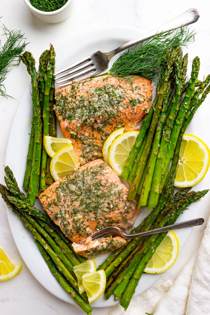 overhead shot of lemon dill salmon with asparagus on a white platter