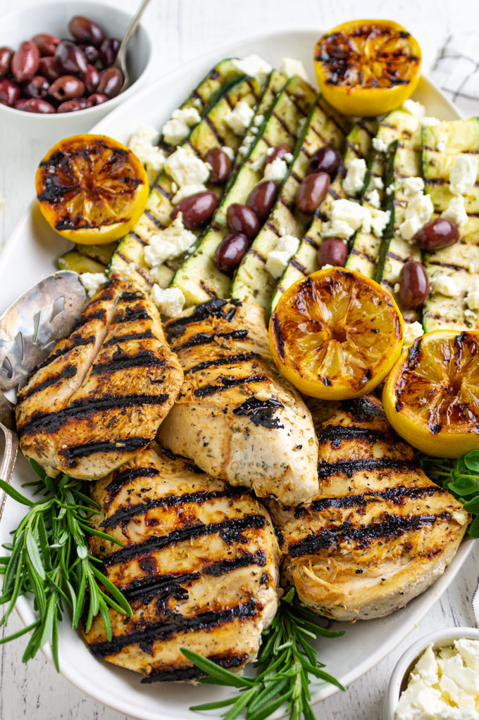 angled shot of Greek grilled chicken with zucchini on a platter.