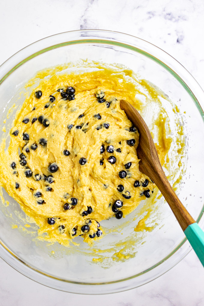 blueberry muffin batter being mixed in a bowl.
