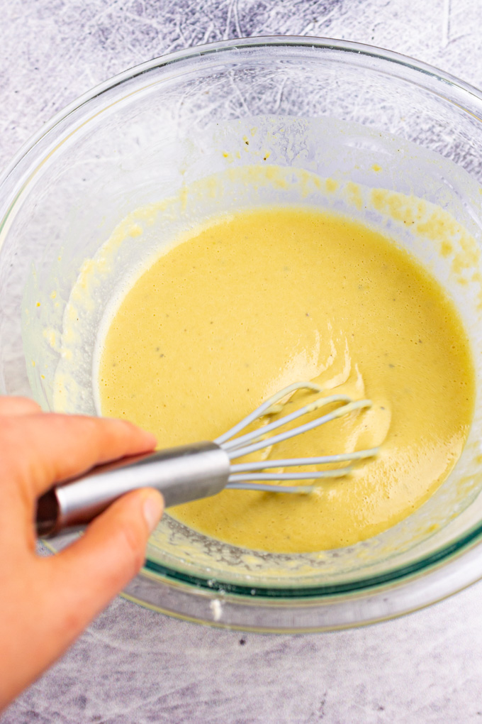 socca batter in a bowl being whisked.