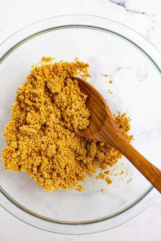 graham cracker crumbs in a mixing bowl with a wooden spoon