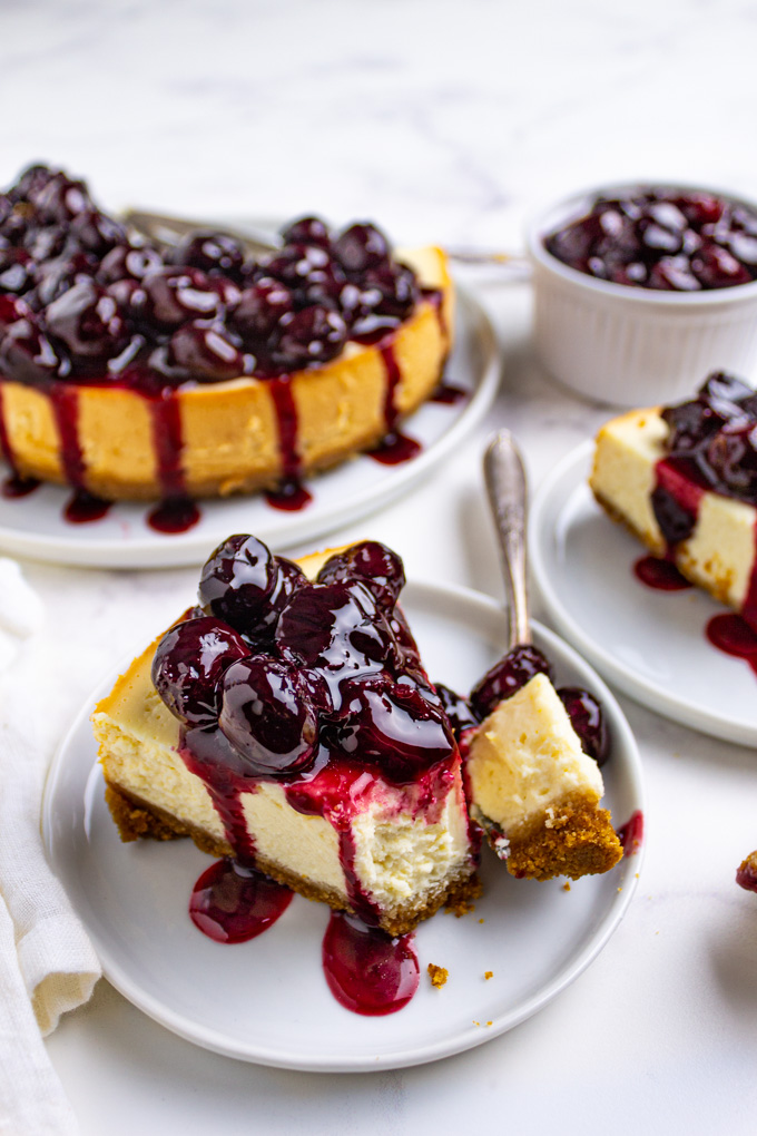 Slices of instant pot cheesecake topped with cherries, on a white background.