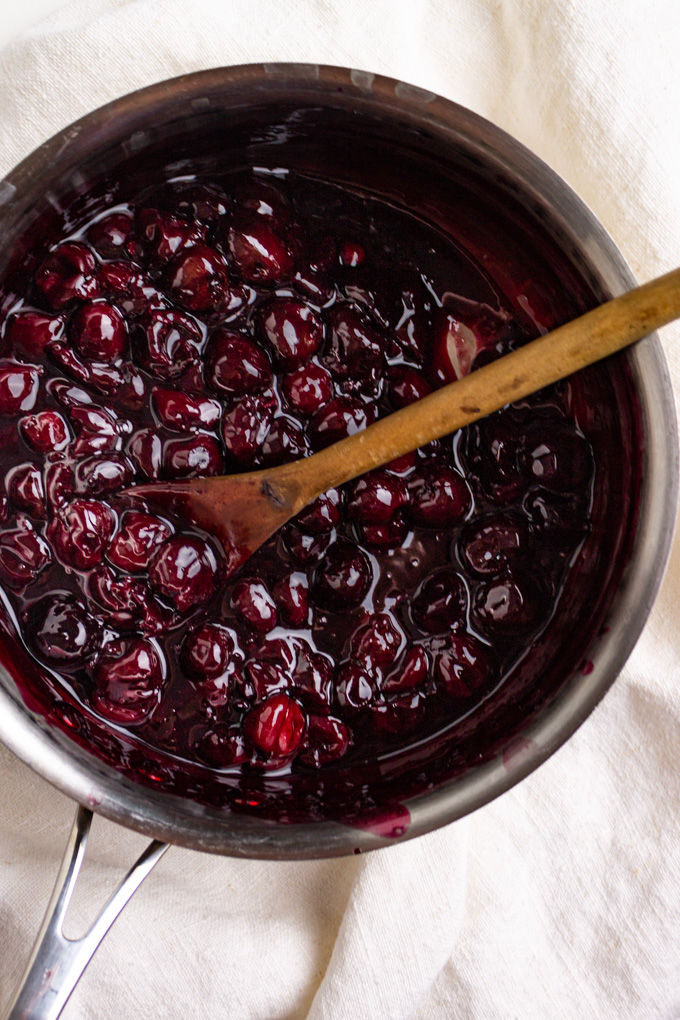 cherry sauce in a sauce pot, with a wooden spoon.
