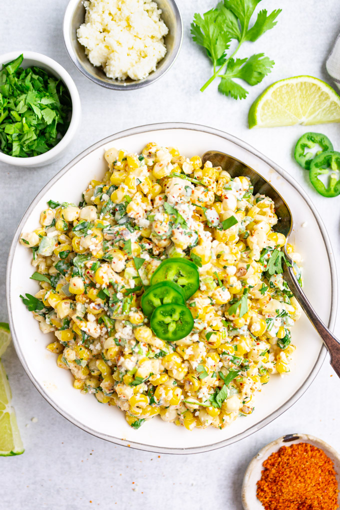 Mexican street corn salad in a serving bowl with jalapeno slices on top.