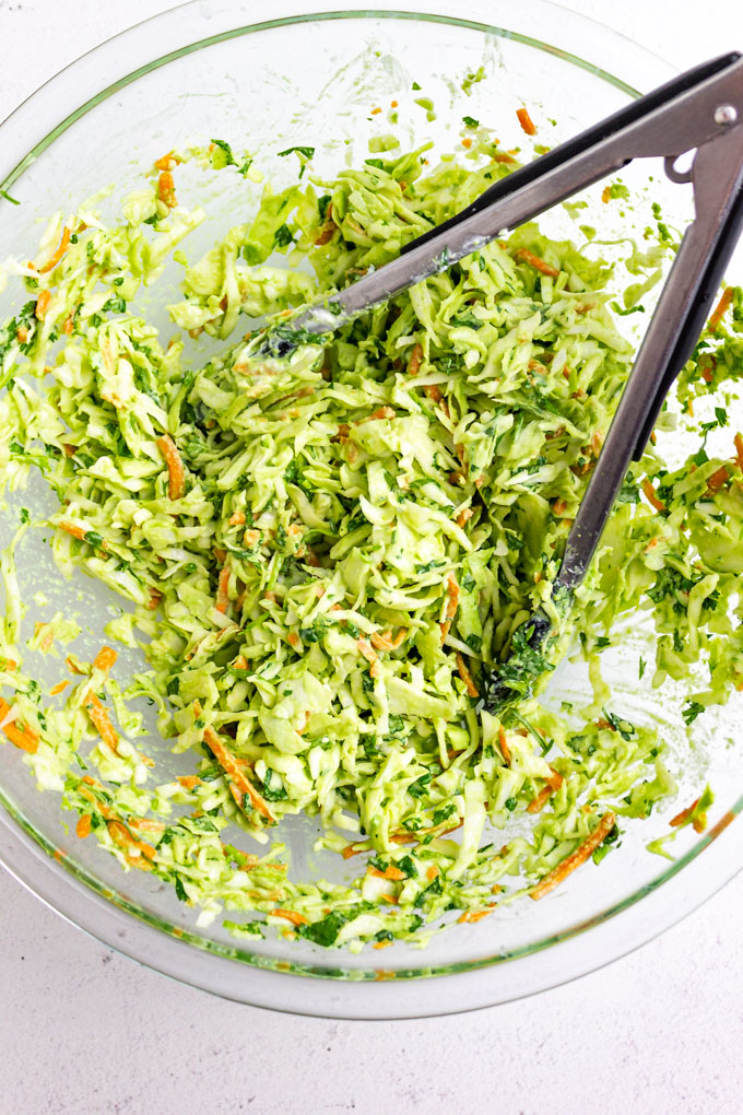 jalapeno cilantro slaw mixed up in a mixing bowl, with tongs.