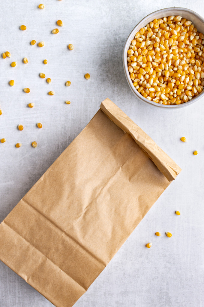a lunch paper bag on it's side, and folded over with popcorn kernels in a bowl