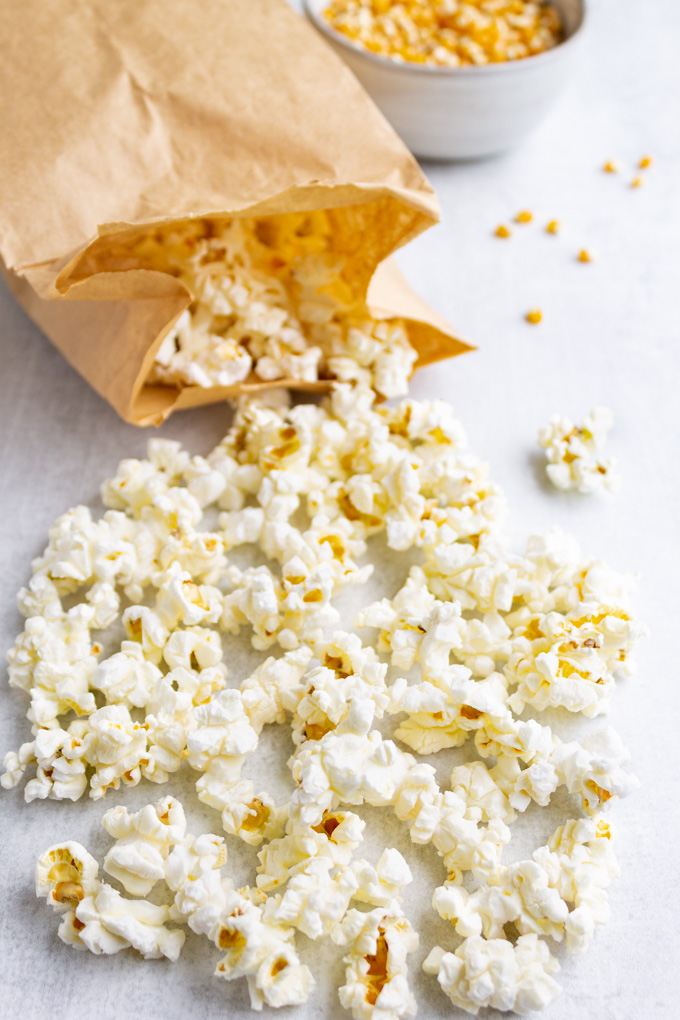 microwave paper bag popcorn at a close up angle, with popcorn spilling out of the bag.