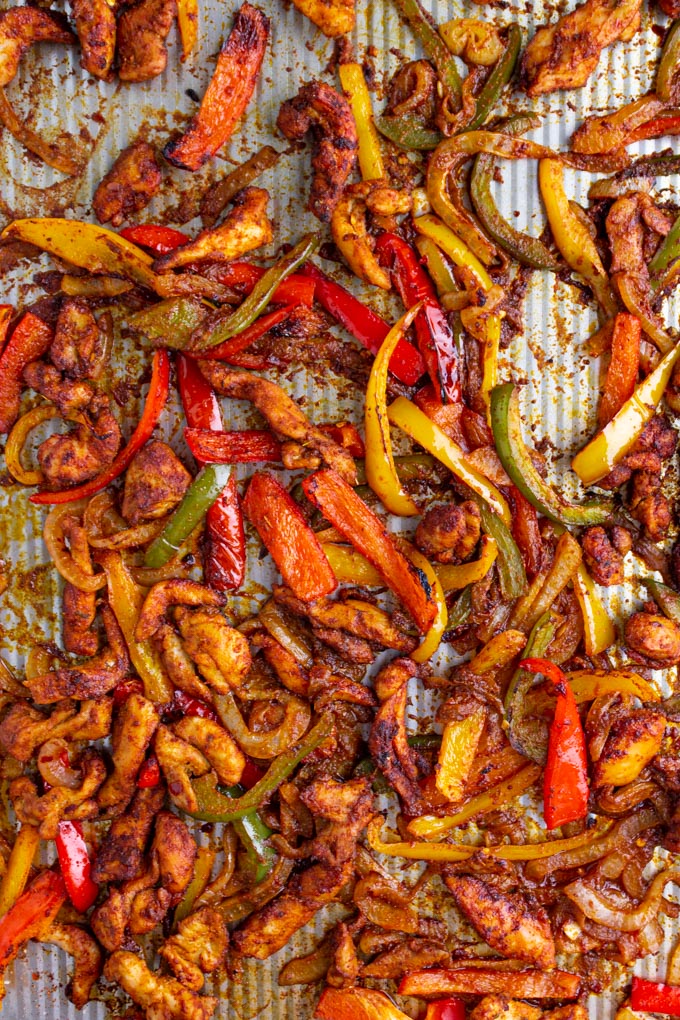 Chicken fajitas on a baking sheet, after being baked.
