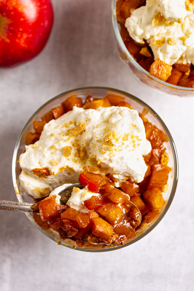 overhead close up shot of apple pie parfaits with a spoon serving up some sautéed apples.