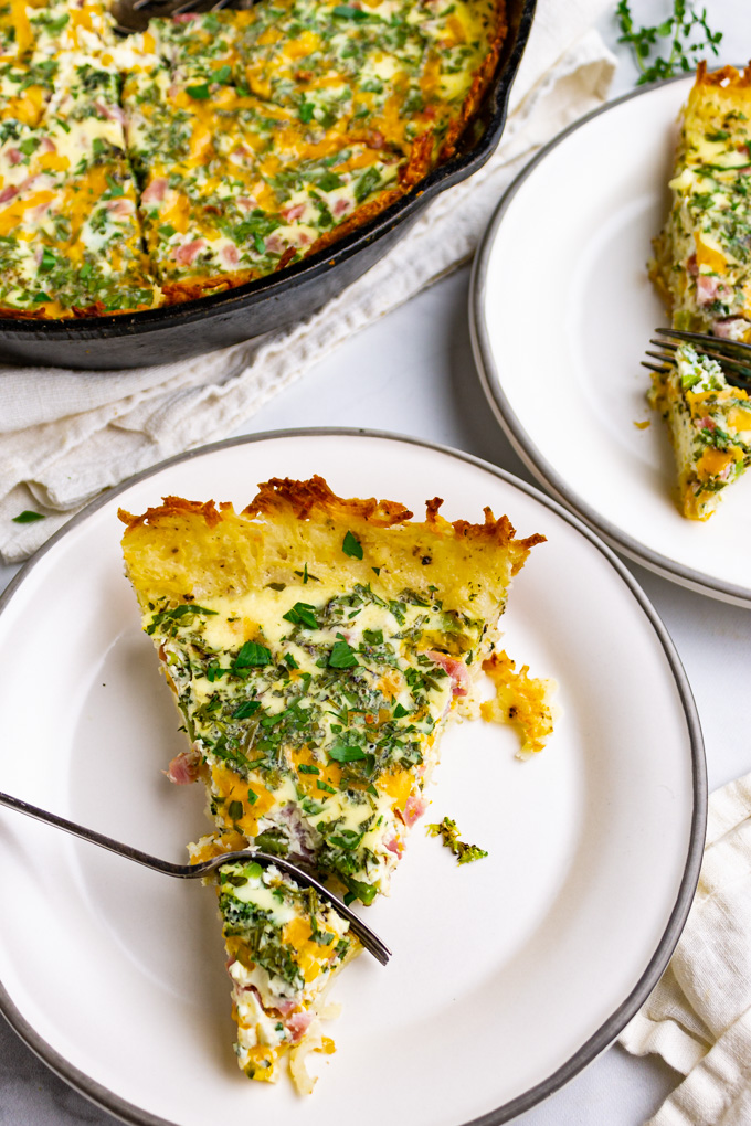closeup angled shot of potato crust quiche with ham and broccoli. A fork is taking a slice out of the quiche.