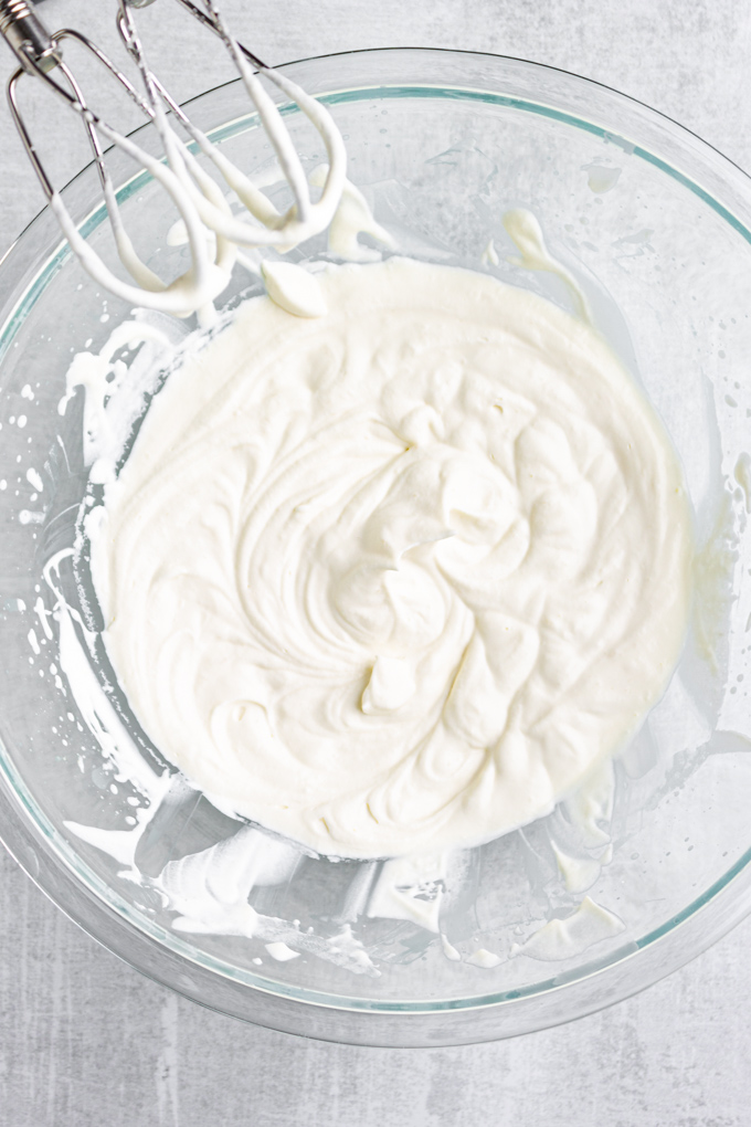a bowl of whipped cream with whisks from an electric hand mixer.