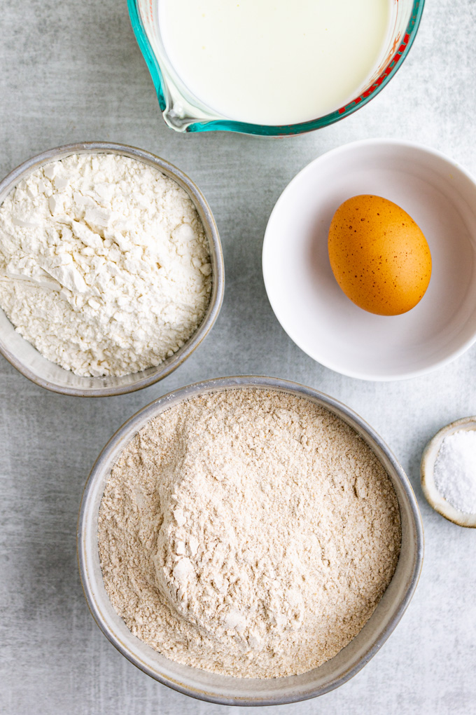 Ingredients in bowls: whole wheat flour, all purpose flour, an egg, buttermilk, and kosher salt.