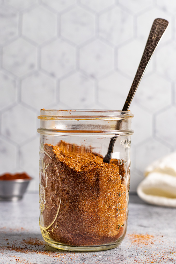 homemade fajita seasoning in a mason jar, with the handle of a spoon sticking out of the mason jar.