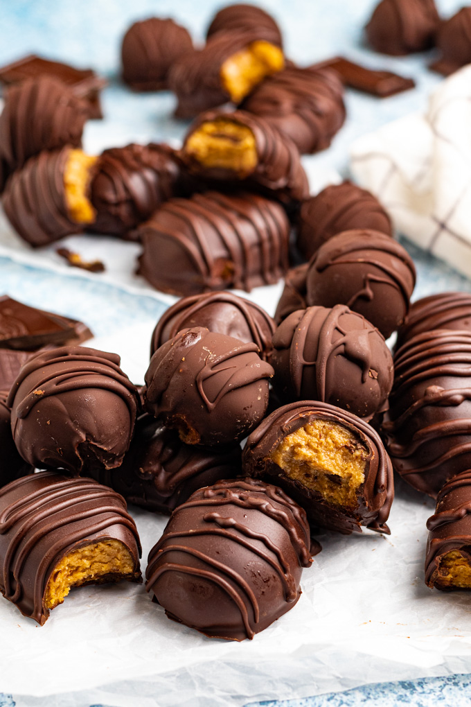 close up angled shot of peanut butter eggs with peanut butter balls. There are bites taken out of some of the eggs.