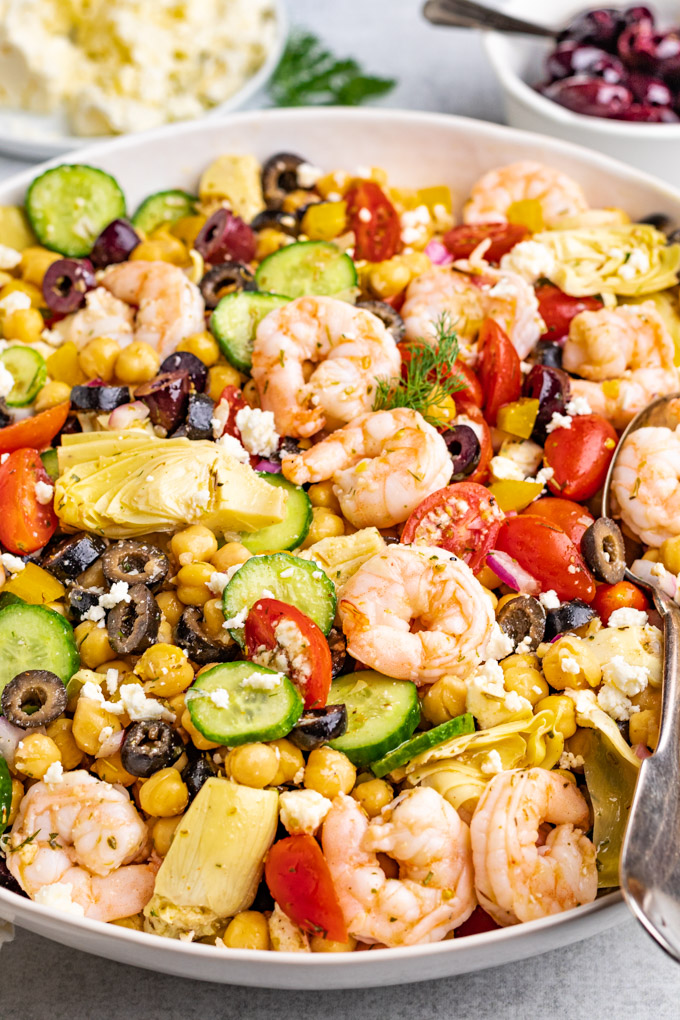 Angled close up shot of Greek chickpea salad with shrimp in a large serving bowl.